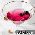 A blueberry lemon drop martini on a white marble table.