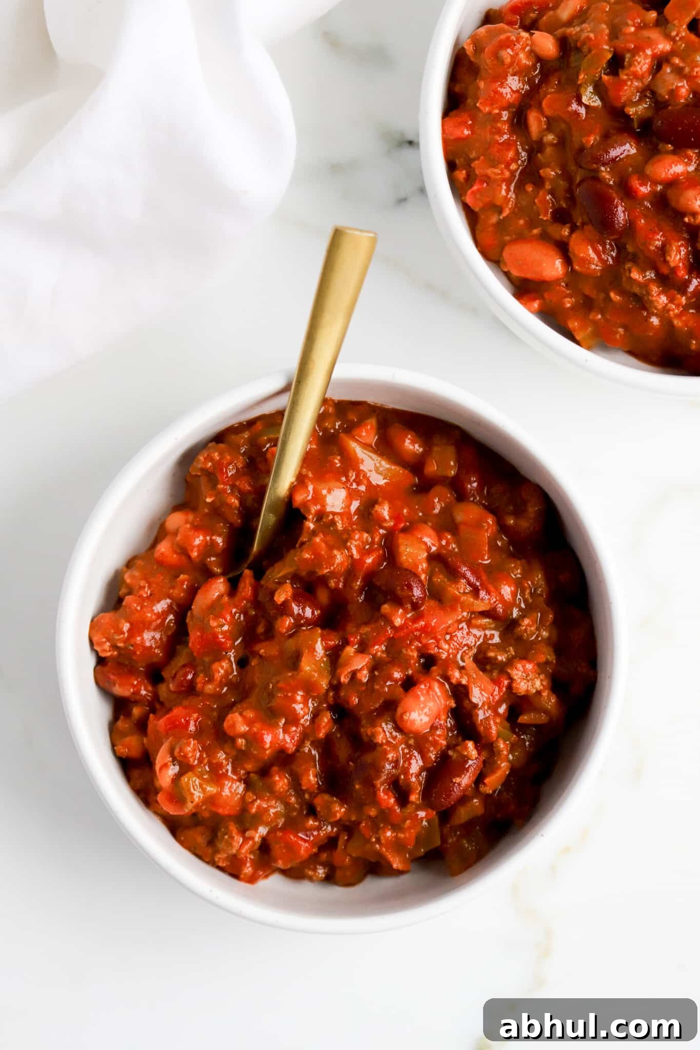 Wendy’s Copycat Chili Recipe: Make the Famous Secret Chili at Home 2 top down view of wendy's chili recipe in a white bowl with gold spoon