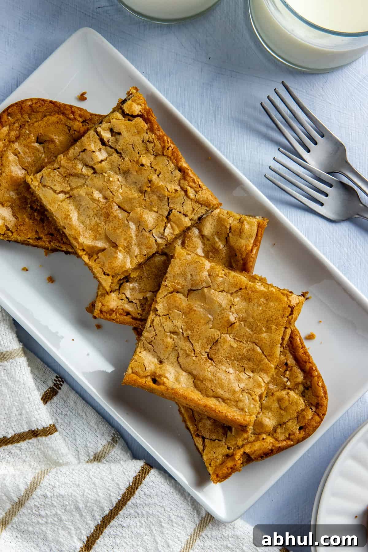 Several baked and sliced blondies stacked on a white rectangular platter.