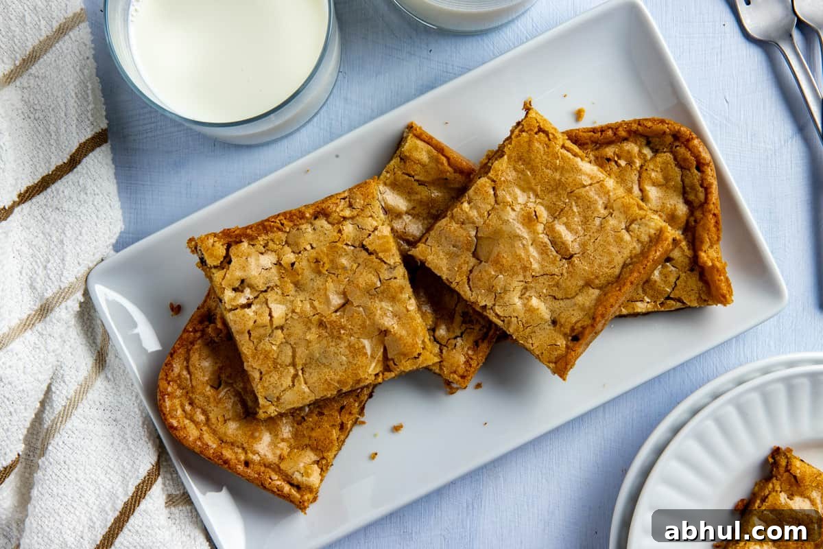 Several baked and sliced blondies stacked on a white rectangular platter.