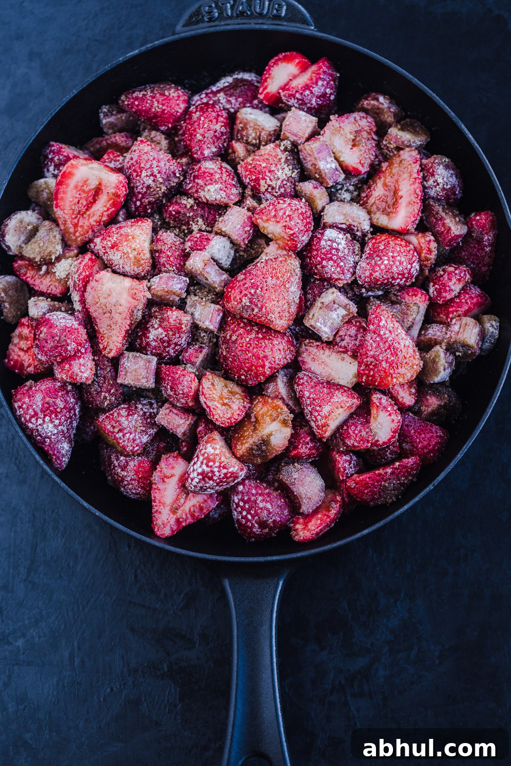 In process shot of the strawberry-rhubarb filling mixed with flour, sugar and cinnamon, in a skillet.