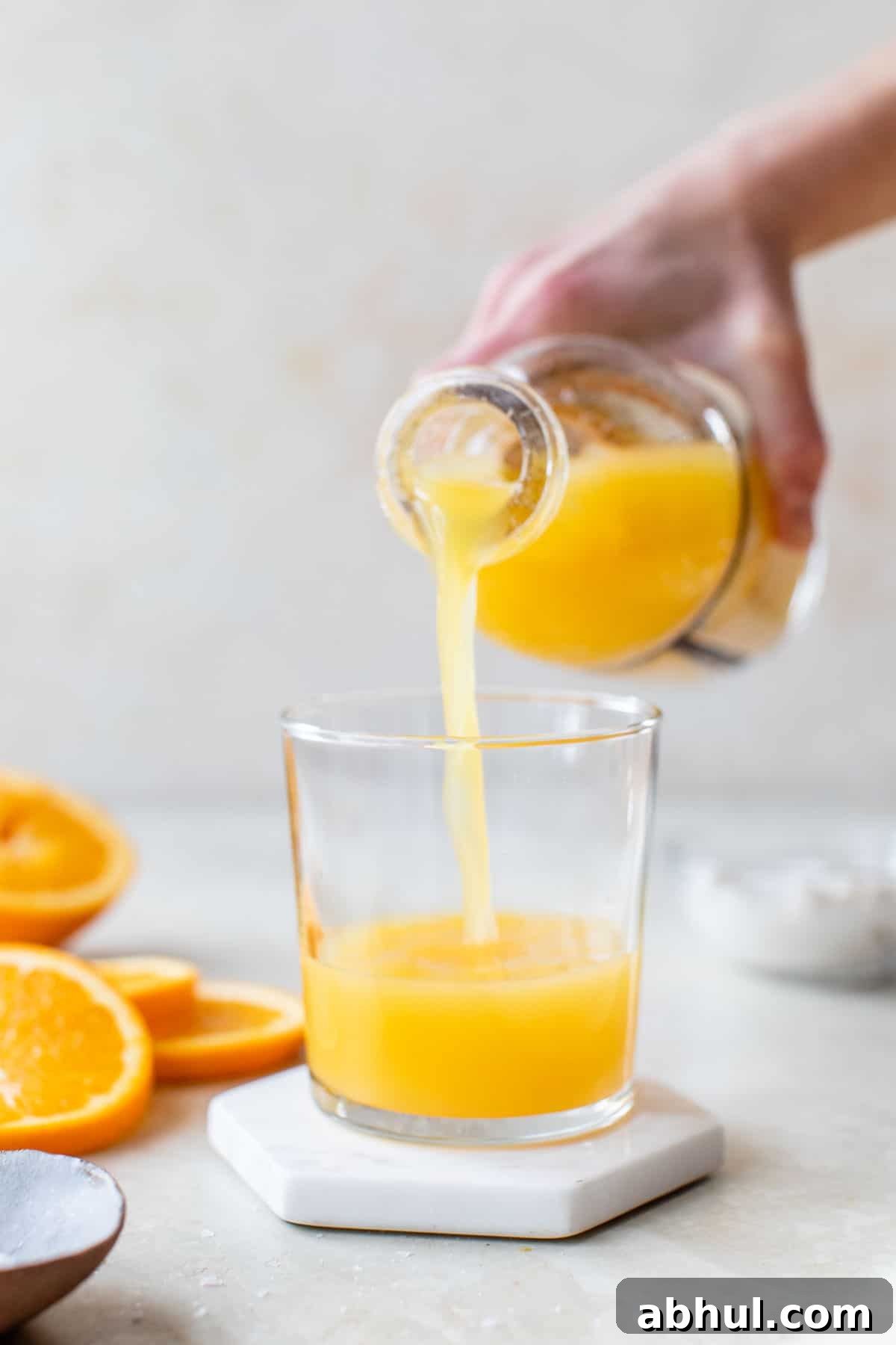 someone pouring orange juice from a bottle into a glass
