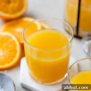 orange juice in a glass surrounded by sliced oranges and a small dish of sea salt