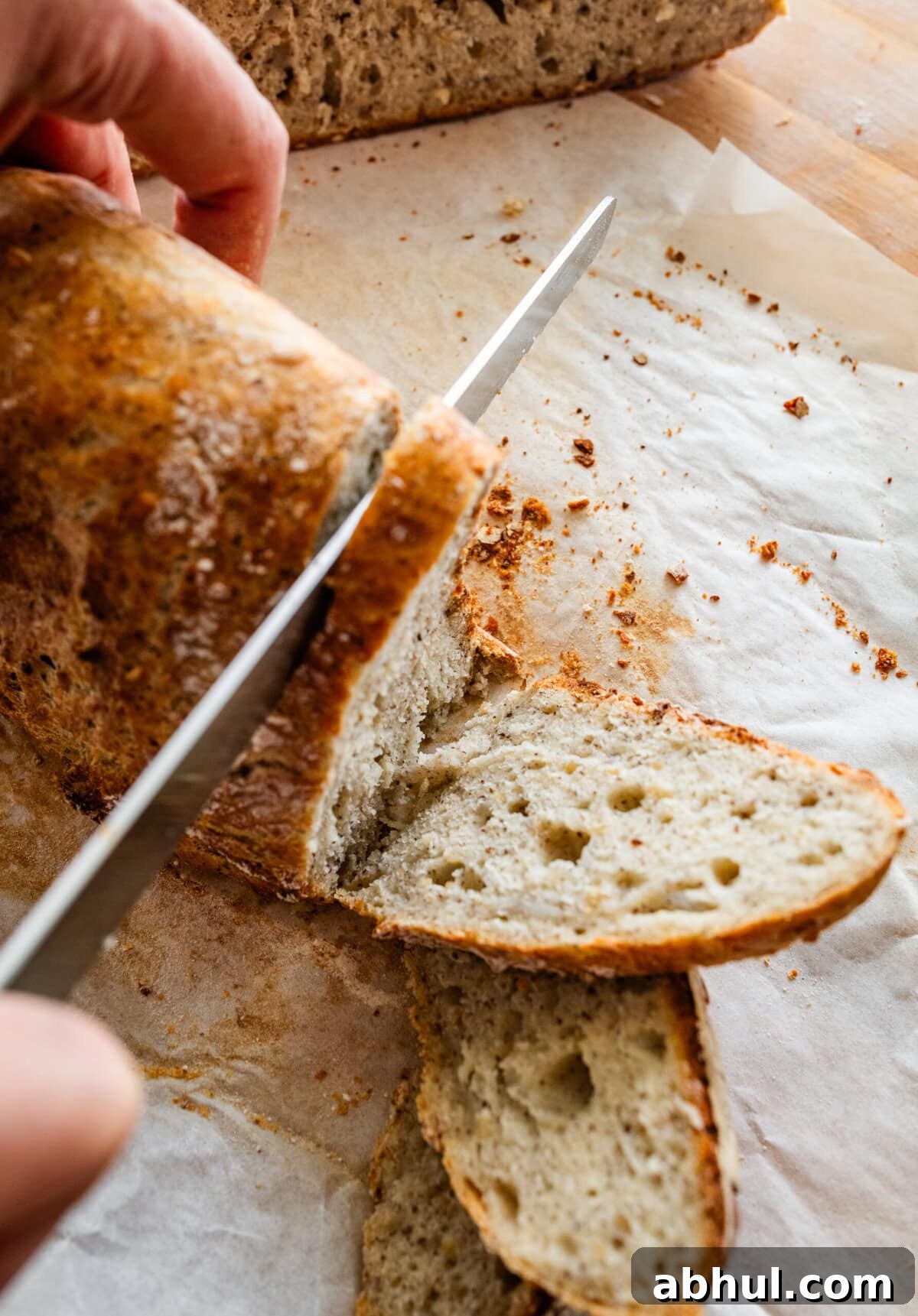 Slicing a loaf of crusty Italian bread on a cutting board. 