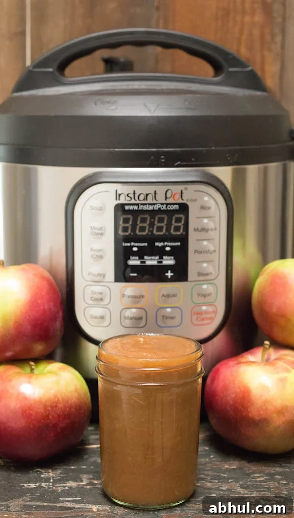 A jar of Instant Pot Apple Butter in front of the appliance and fresh apples.