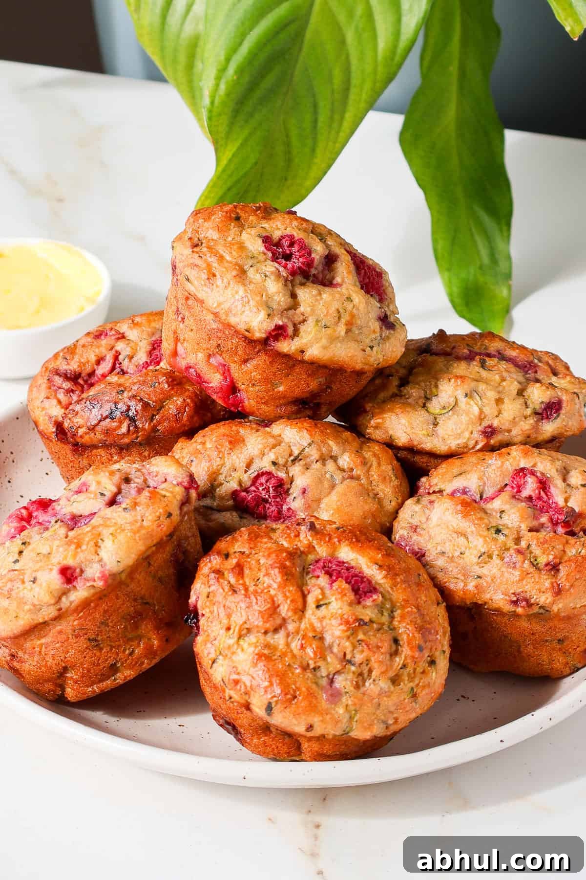Side shot of banana raspberry muffins on a plate.