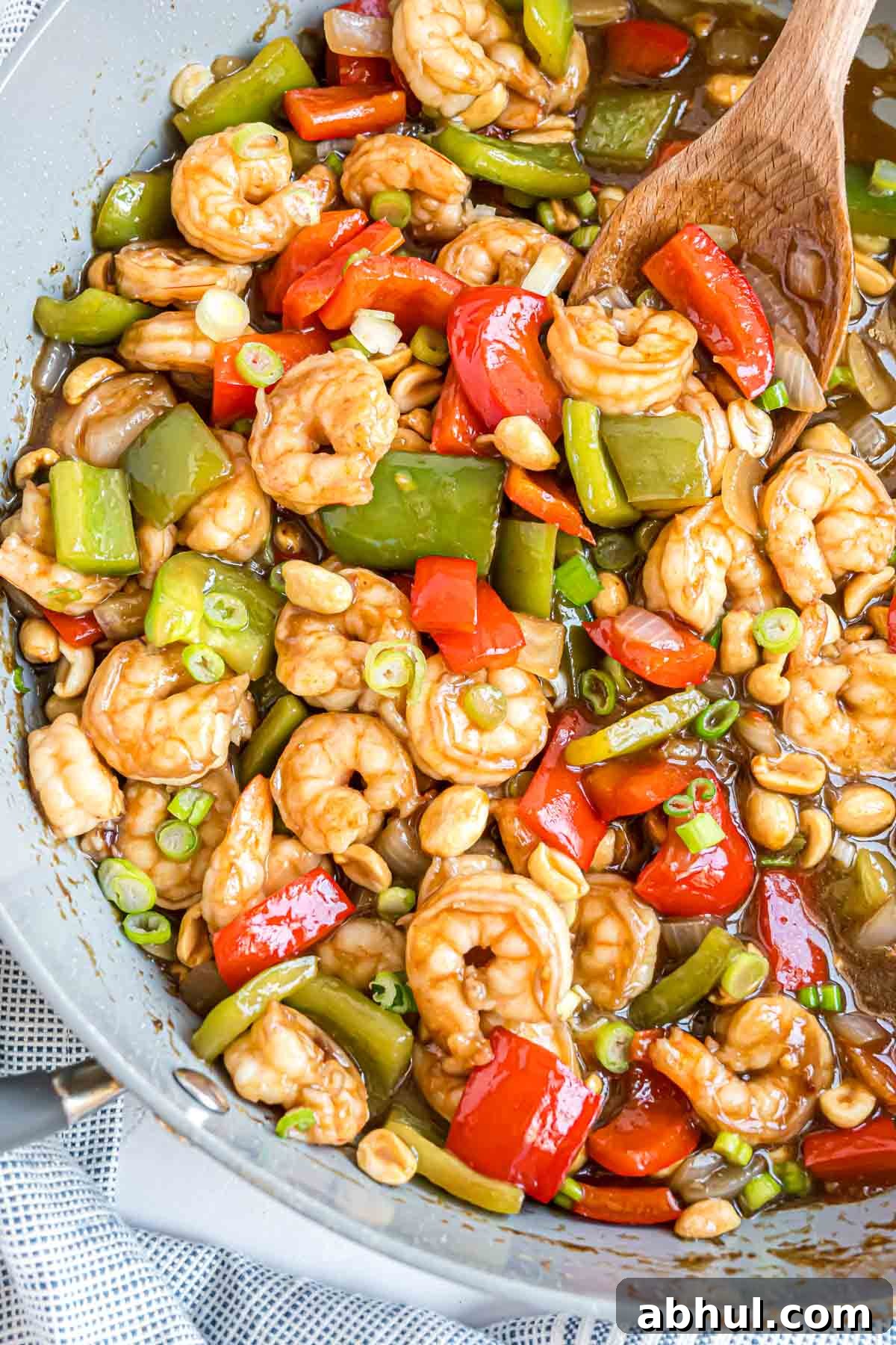 Green onions and peanuts added to cooked kung pao in frying pan.