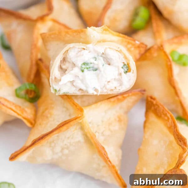 Air fryer crab rangoons, one split open to show filling.