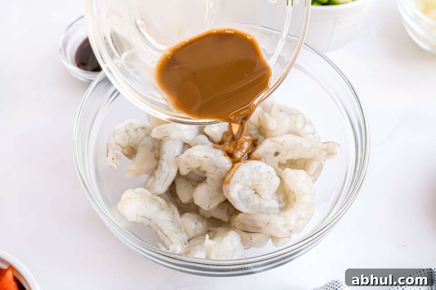 Marinade being poured onto uncooked shrimp.