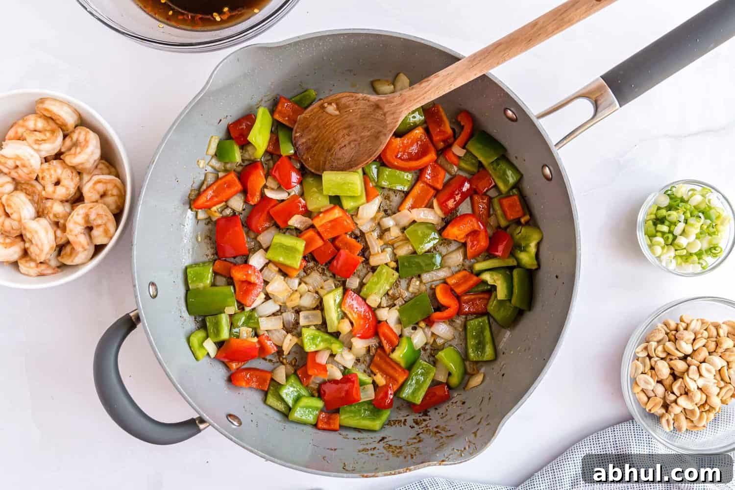 Vegetables being stir fried in a large frying pan.