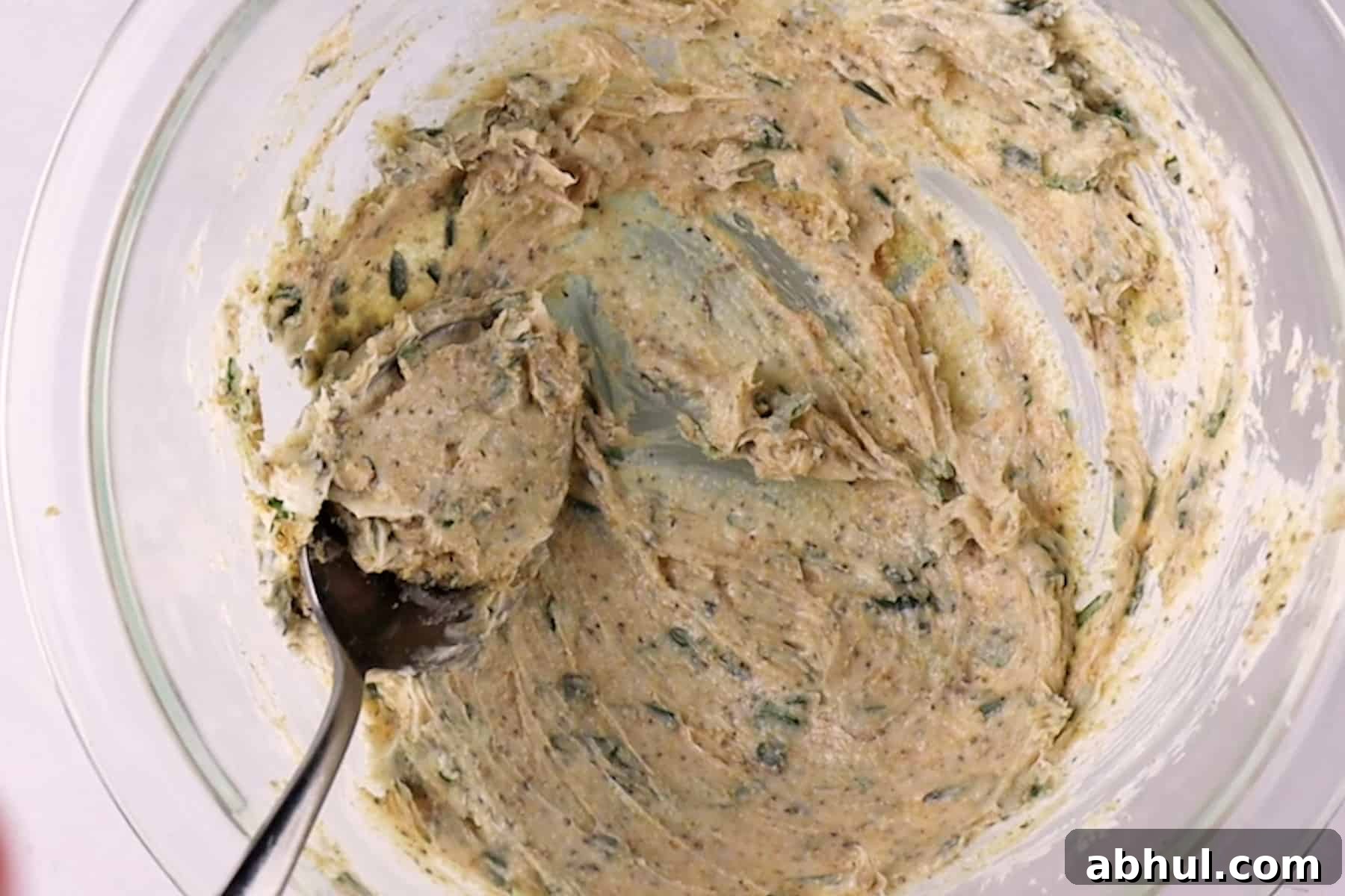 Mixing herb butter in a glass bowl.