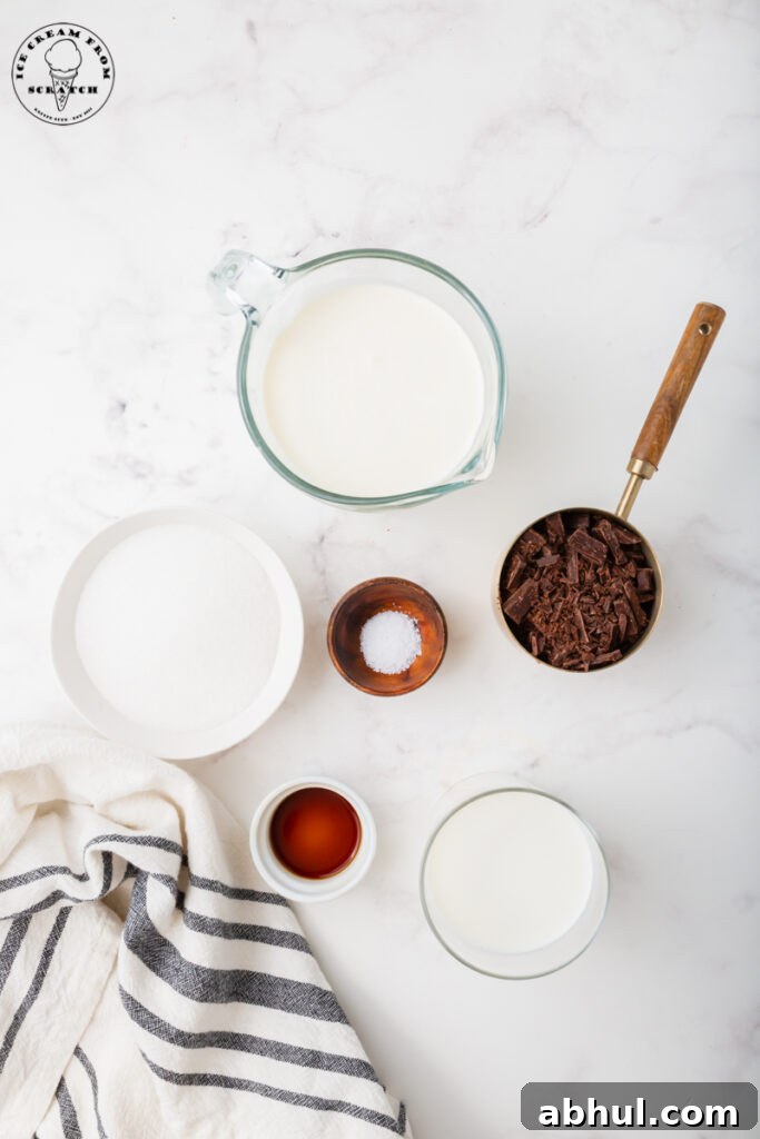 ingredients for homemade chocolate chip ice cream are in separate bowls on a marble counter. Includes chopped chocolate, sugar, and cream.
