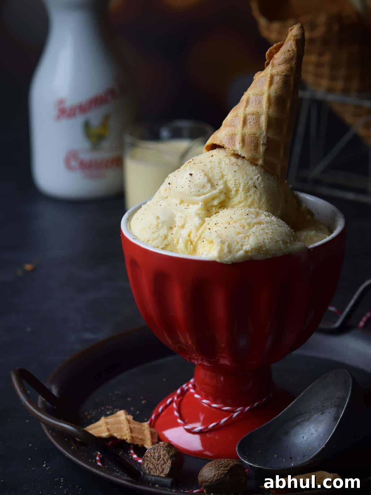 Ice cream in a red cup with an ice cream cone on top.
