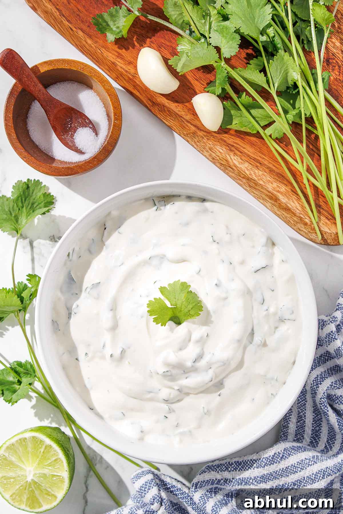 A bowl of creamy cilantro dip with lime, garlic, and salt on a kitchen counter.