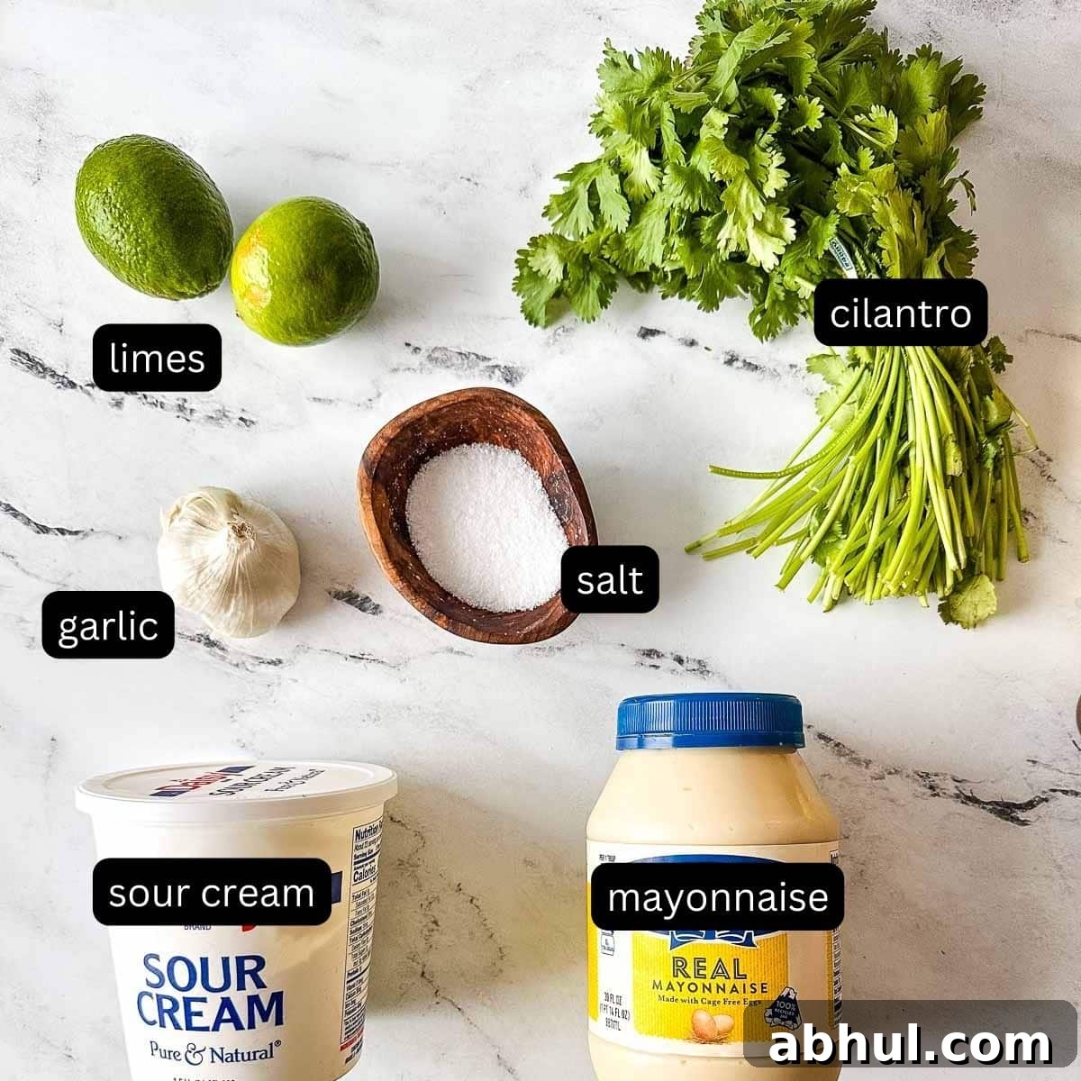 The labeled ingredients for cilantro lime crema sit on a white marble counter.