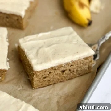 a close up of a single slice of the brown butter banana sheet cake on a sheet cake pan.