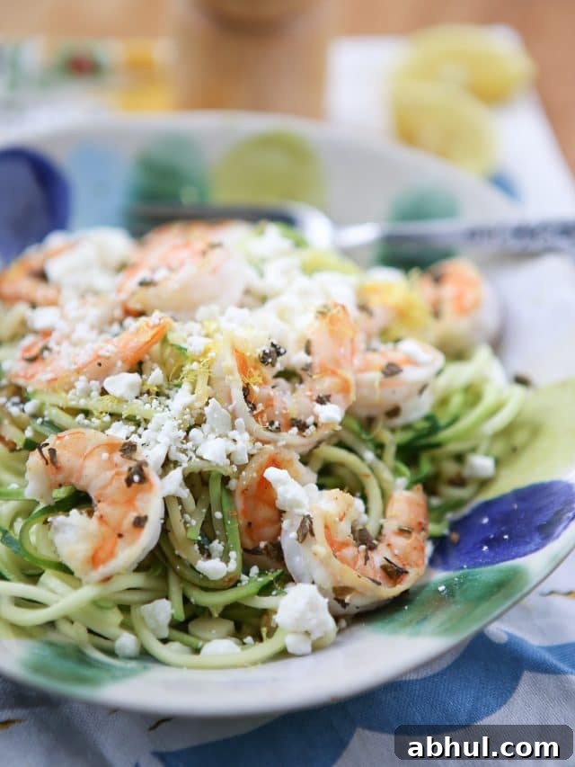 bowl of zuchinni noodles topped with shrimp and feta cheese