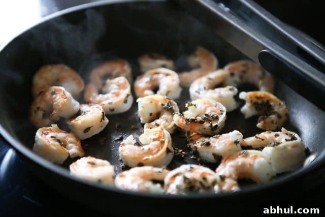shrimp cooking in skillet with seasonings on top