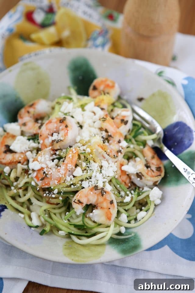 bowl of zuchinni noodles topped with shrimp and feta cheese