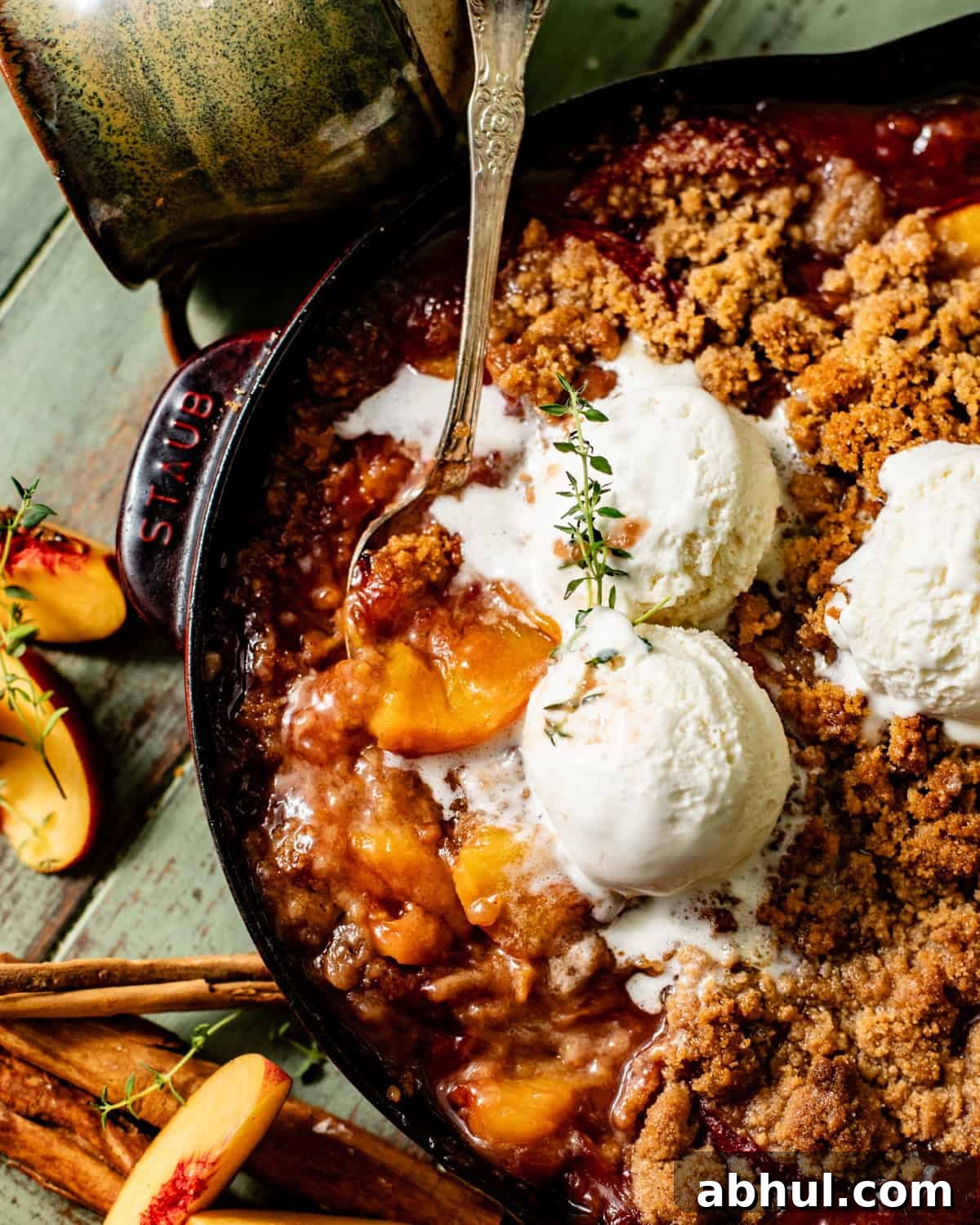 up close photo of a spoon scooping peach crumble out of the skillet.