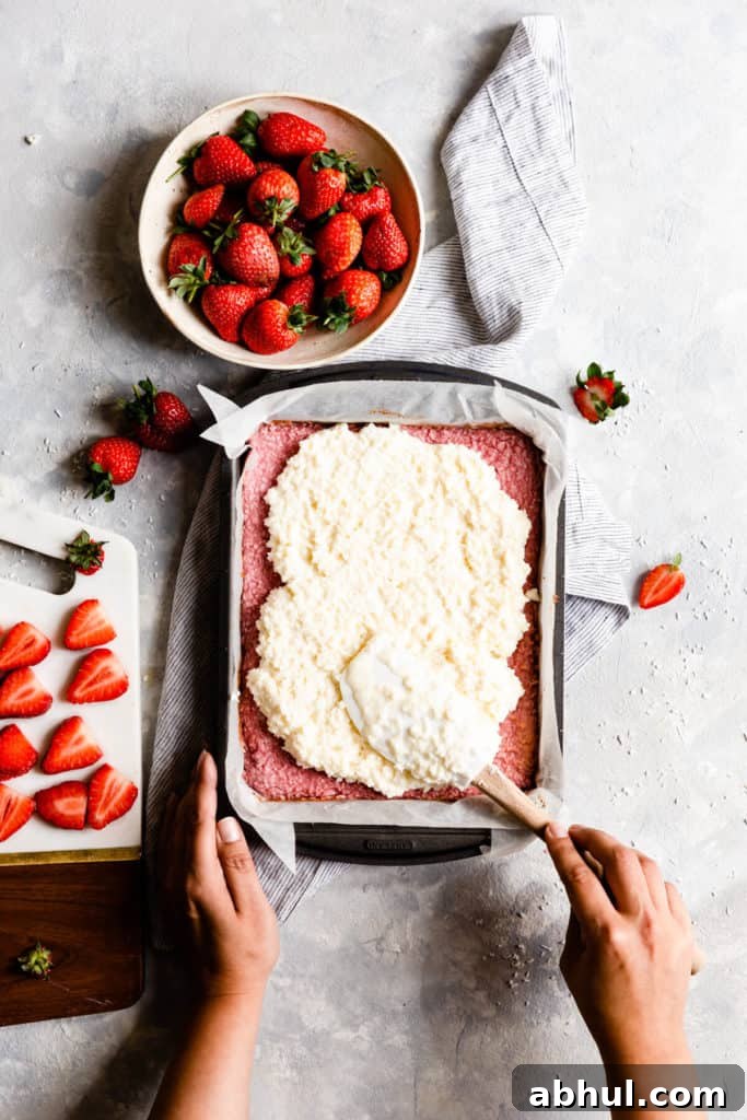 Strawberry Coconut Frozen Squares: Refreshing No-Bake Treat 18 top view showing a person spreading coconut mixture into baking tin