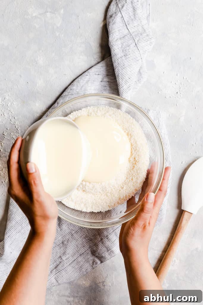 Strawberry Coconut Frozen Squares: Refreshing No-Bake Treat 8 overhead shot of condensed milk being poured into bowl with coconut