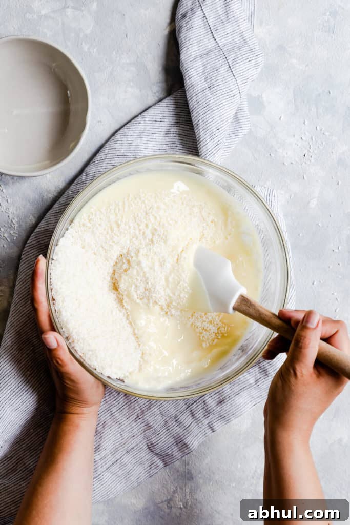 Strawberry Coconut Frozen Squares: Refreshing No-Bake Treat 9 overhead shot of coconut and condensed milk being mixed together in a bowl