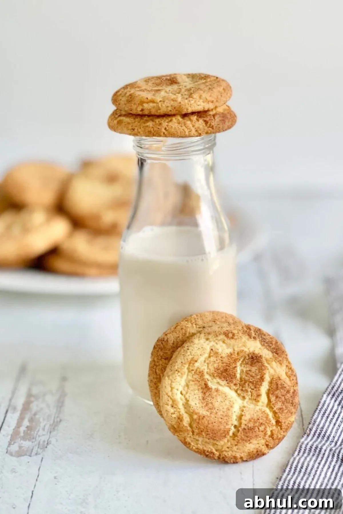 A glass jar of almond milk with a gluten free snickerdoodle on top and one in front of it.