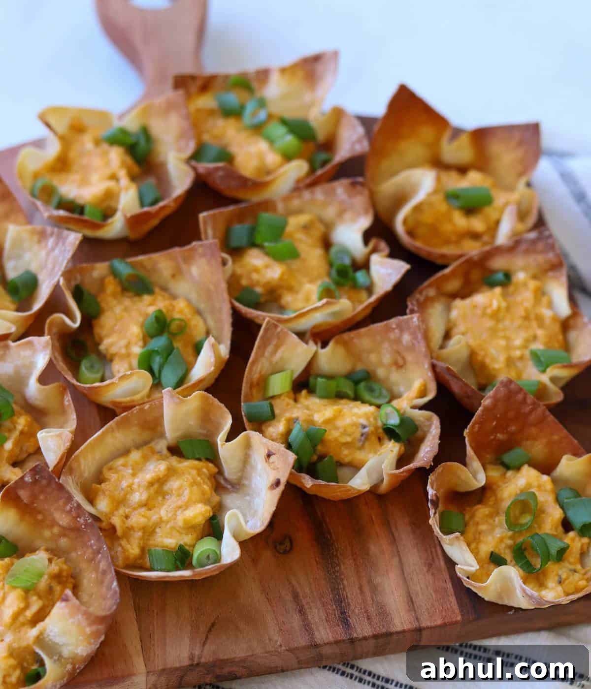 Buffalo chicken wontons on wooden platter.
