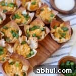 Wonton cups filled with buffalo chicken and green onion on platter.