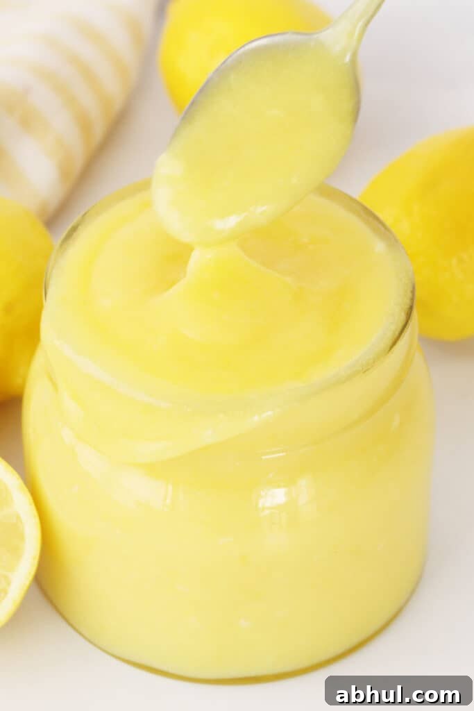 The best lemon curd recipe in a small jar with a spoon.