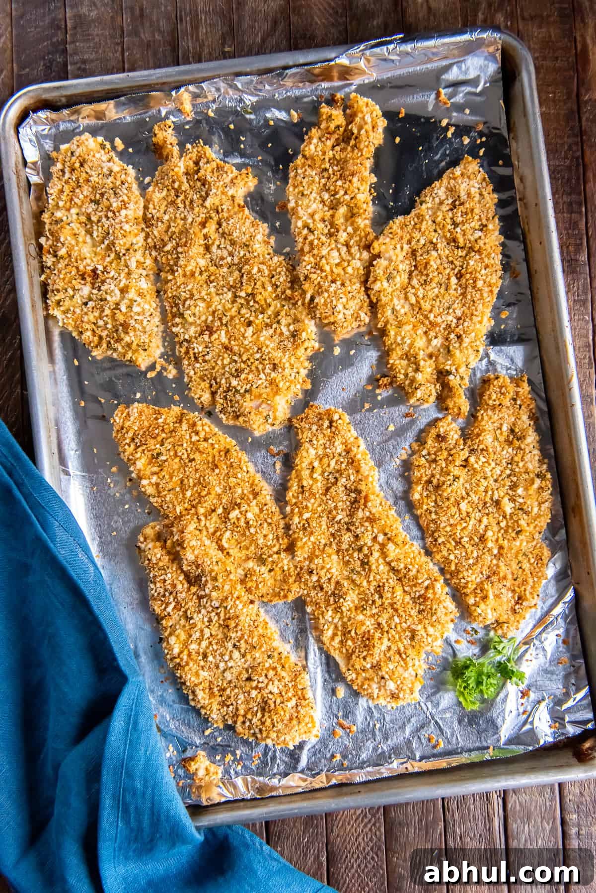 Crispy Oven-Baked Fish Fillets with Parmesan Crust 3 A top down shot of crispy baked fish filets on a foil lined baking sheet.