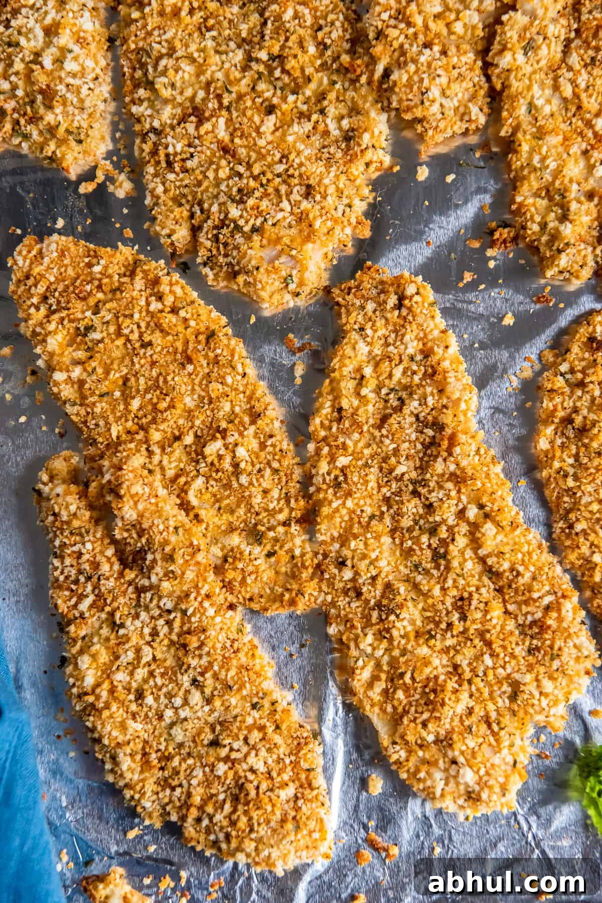 Crispy Oven-Baked Fish Fillets with Parmesan Crust 8 A top down close up shot of crispy baked fish filets on a foil lined baking sheet.