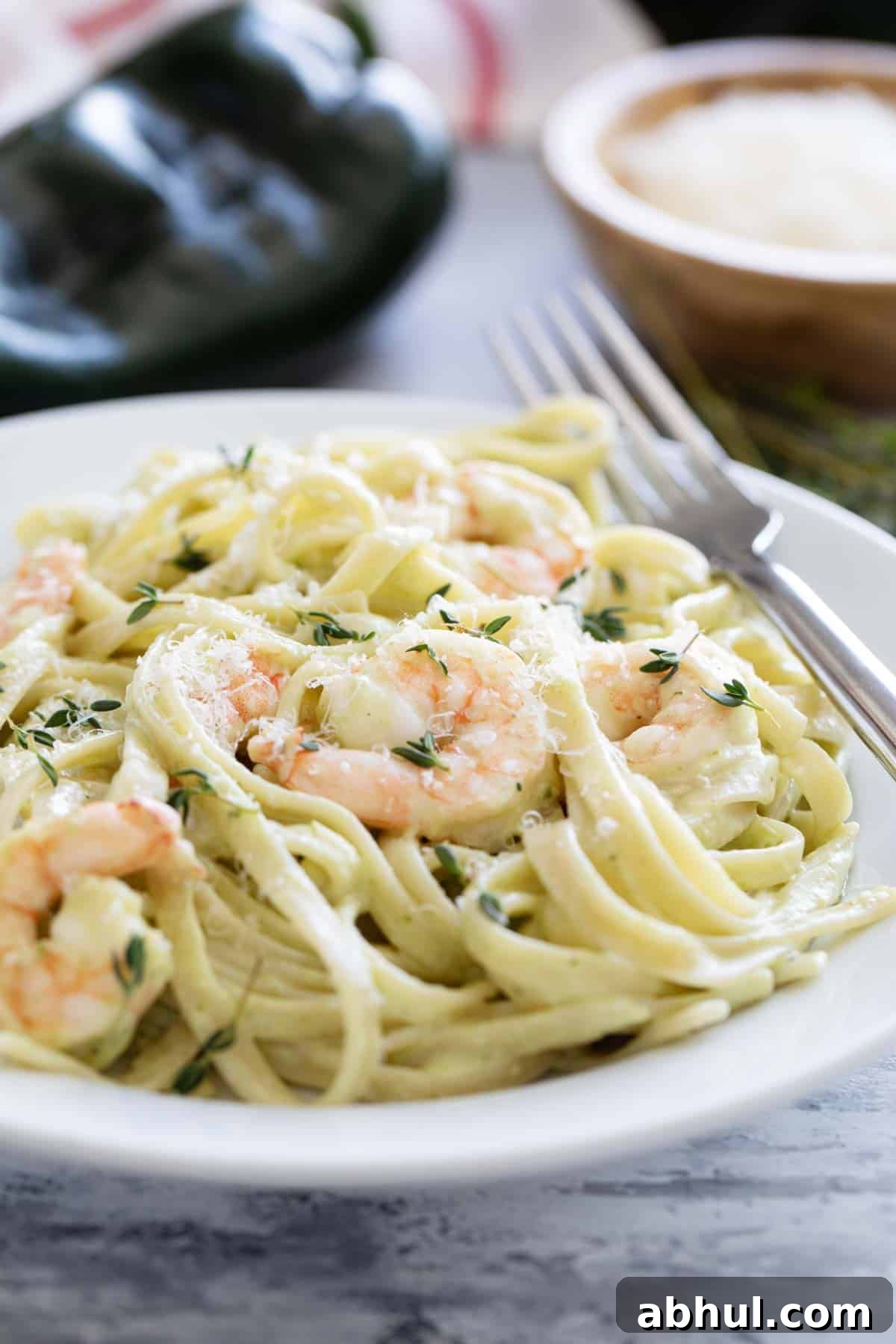 Bowl of shrimp pasta with poblano cream sauce topped with parmesan and fresh thyme.