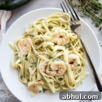 White plate topped with shrimp pasta with poblano cream sauce and a fork.