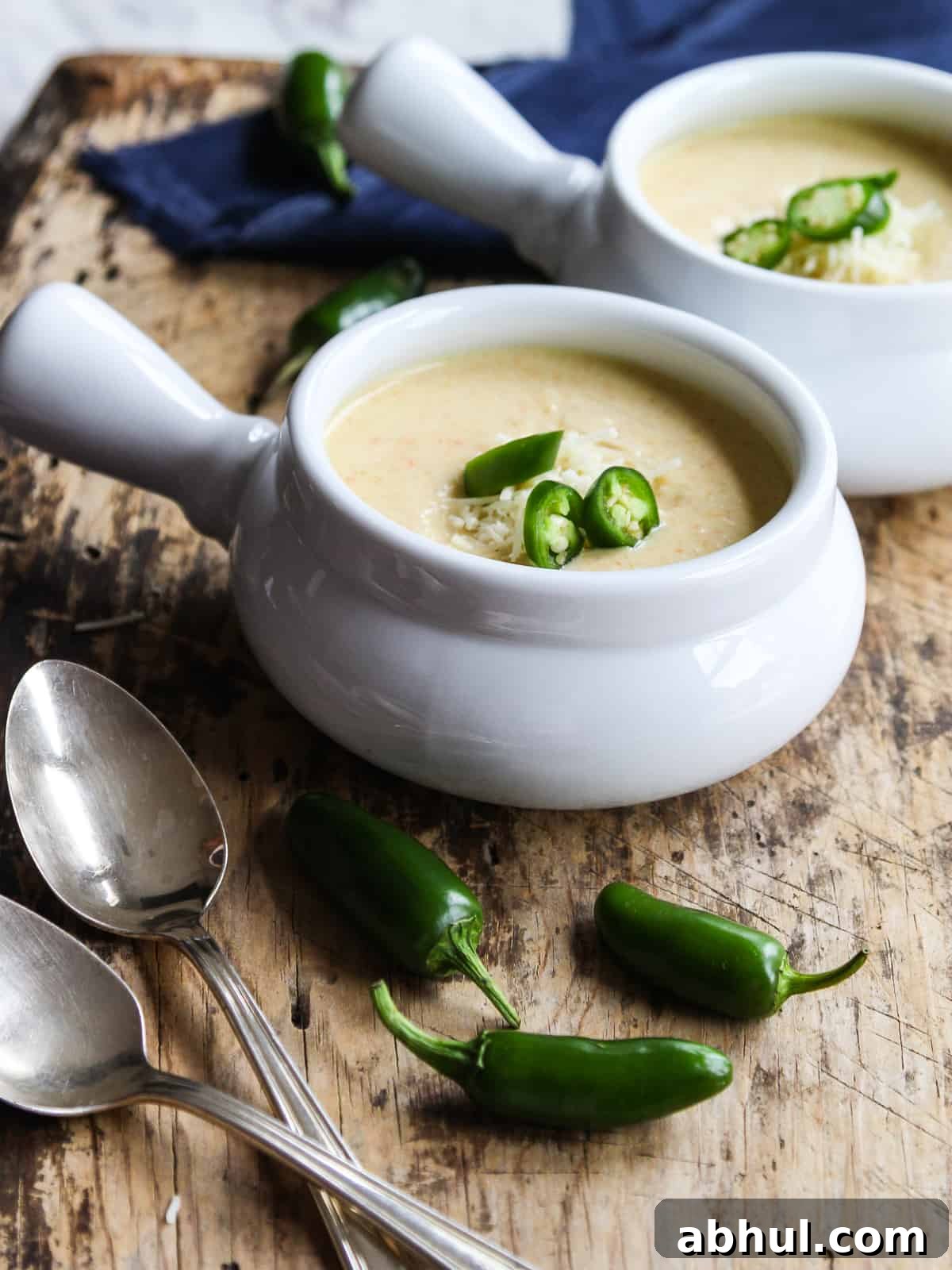 Two bowls of jalapeno popper soup with peppers