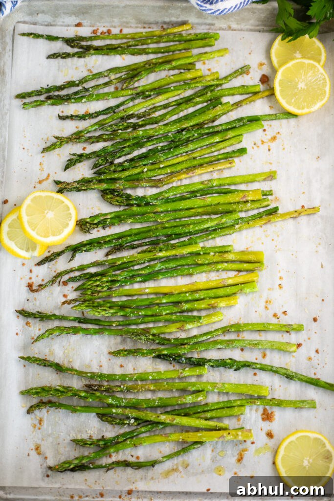Oven roasted asparagus and lemon slices on a baking sheet lined with parchment paper.