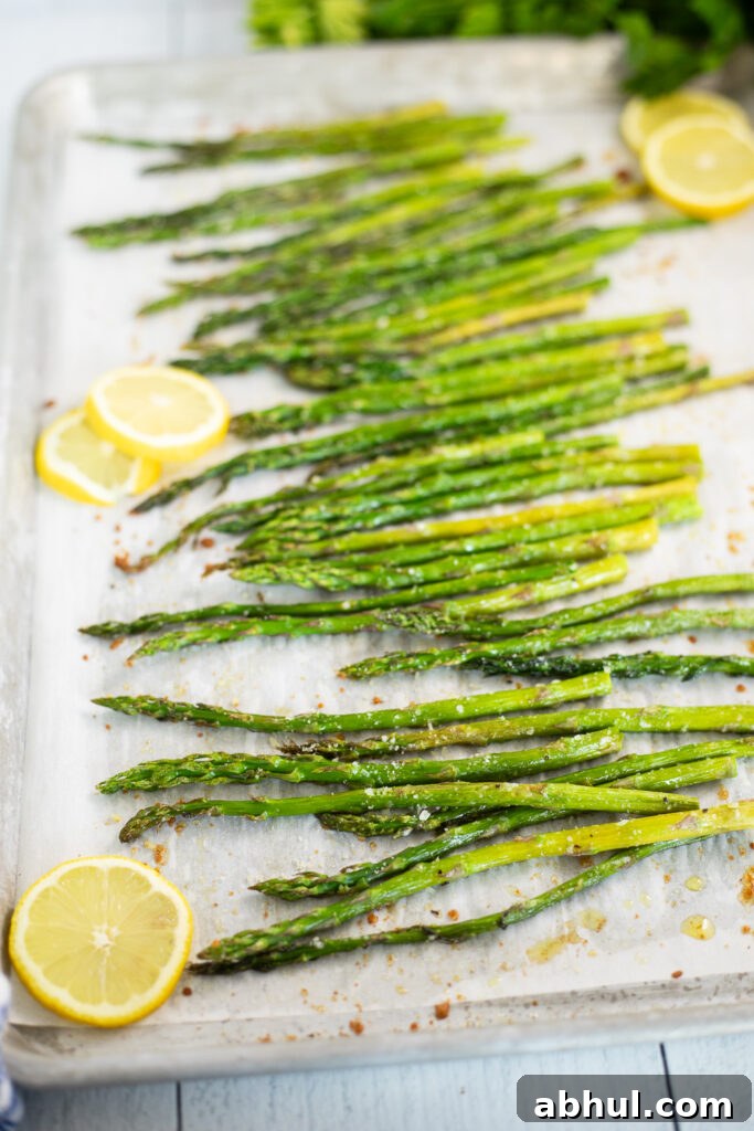 Oven roasted asparagus and lemon slices on a baking sheet lined with parchment paper.