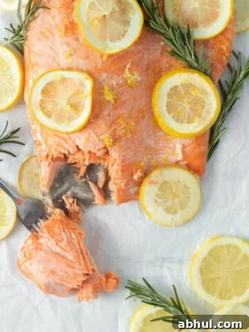 baked lemon butter salmon with lemon rounds on parchment paper.