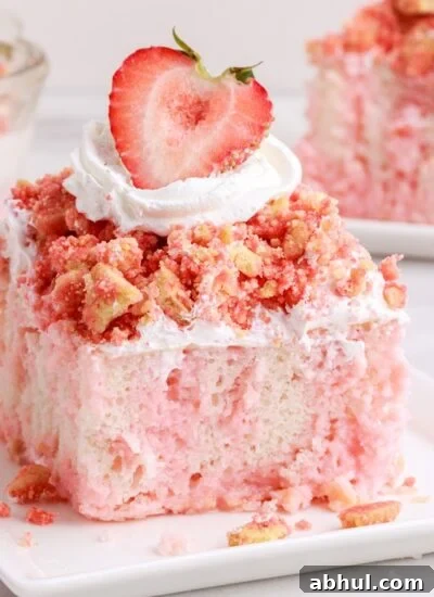 Close up of a slice of Strawberry Crunch Poke Cake showing the marbling colors and garnish, with other pieces of cake in the background.