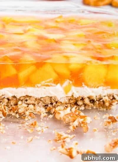 Side view of the peach pretzel salad showing the three layers: pretzel crust, creamy middle, and peach jello with peach chunks.