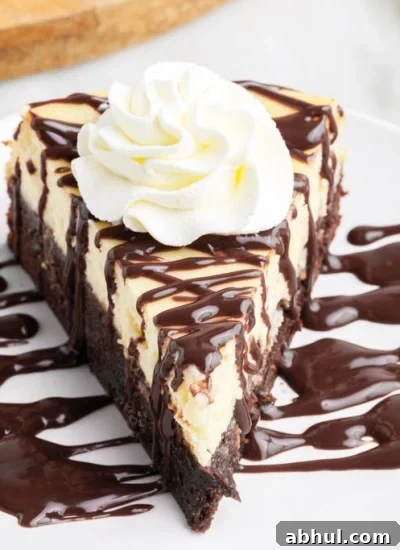 a slice of Brownie Bottom Cheesecake on a small white plate drizzled with chocolate