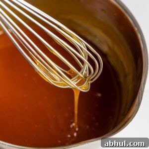 Coconut caramel sauce falling off a whisk into a pan.