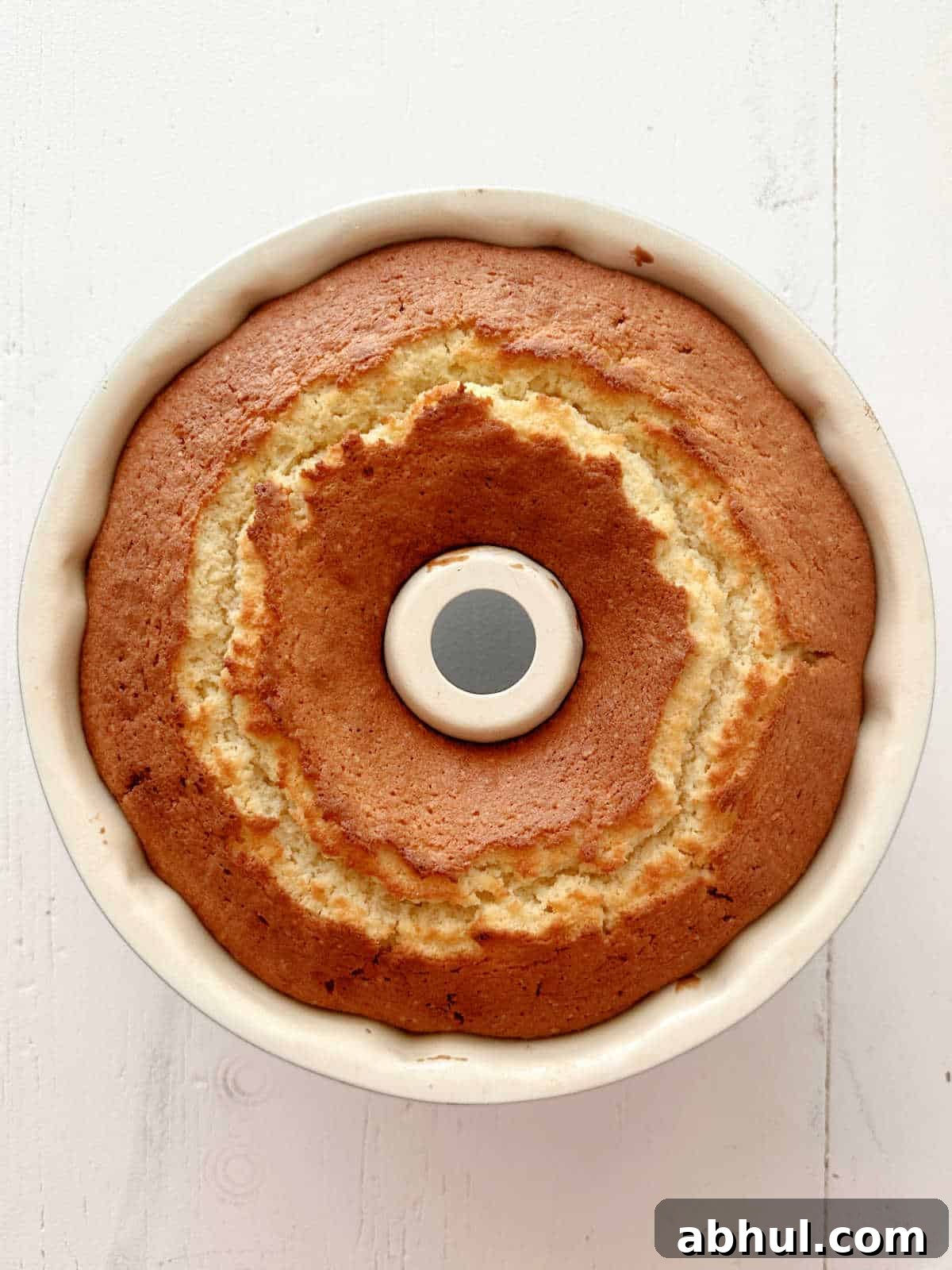 Moist Mango Coconut Bundt Cake Recipe for Tropical Desserts 8 Baked bundt cake in the pan on a white surface. Top view.