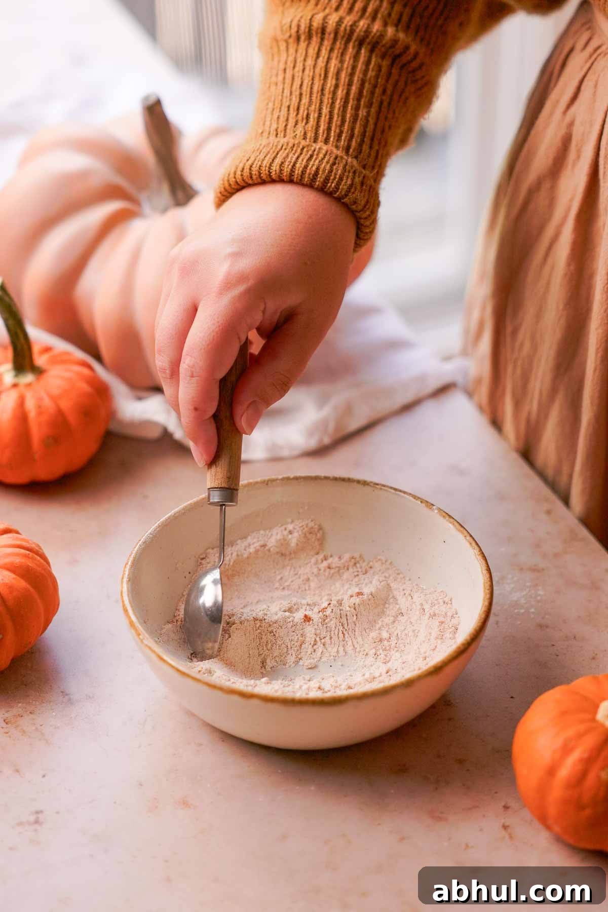 stirring flour, sugar, and cinnamon in a bowl with a measuring spoon
