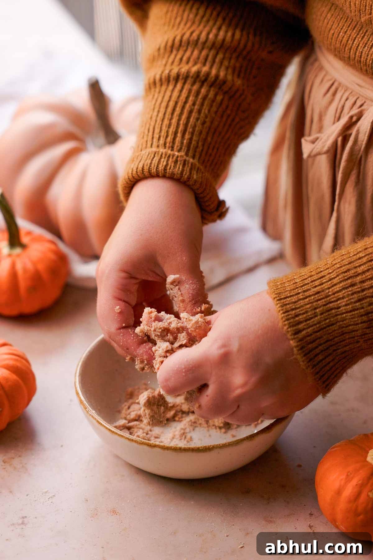 mixing cinnamon streusel with fingers
