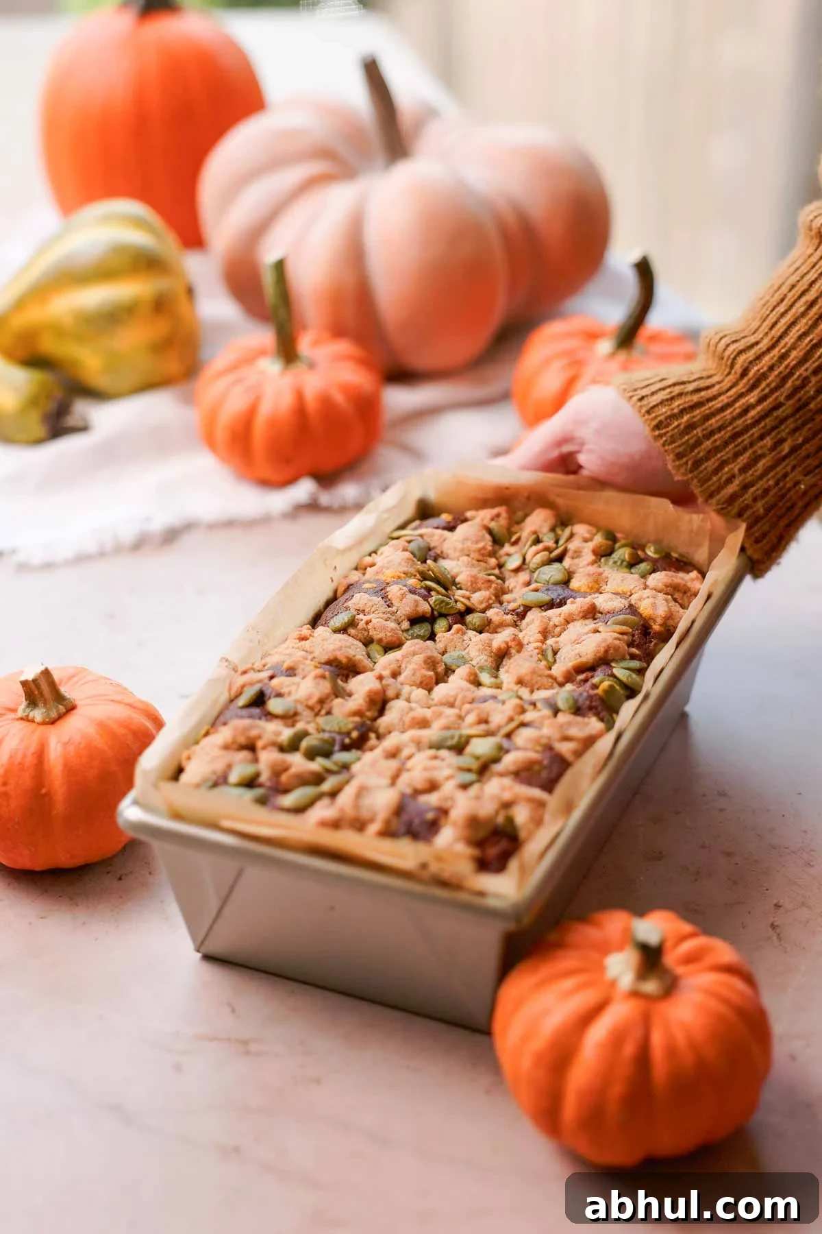 baked cream cheese streusel bread in parchment lined metal loaf tin