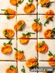 Sliced cake frosted with white frosting and piped mini pumpkins