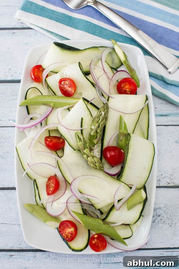 A sliced cucumber salad lies in a white dish on a blue striped towel.