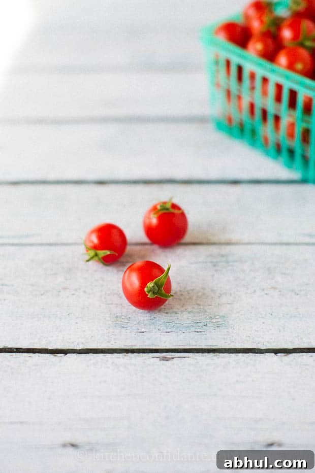 Three cherry tomatoes sit on a table ready to eat.